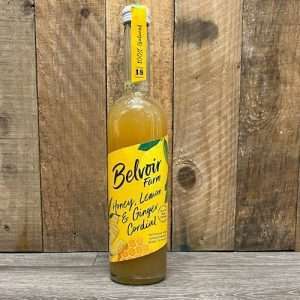 Tall, thin glass bottle with yellow label and golden liquid inside. Handwritten label reads 'belvoir honey, lemon and ginger'